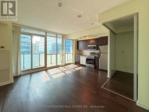 Toronto (Waterfront Communities) condo for rent - A spacious kitchen with dark wood floors and a large window overlooking the city.