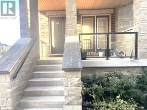 Brampton (Northwest Brampton) townhouse for rent - A house entrance with a stone wall and steps leading to a glass door.