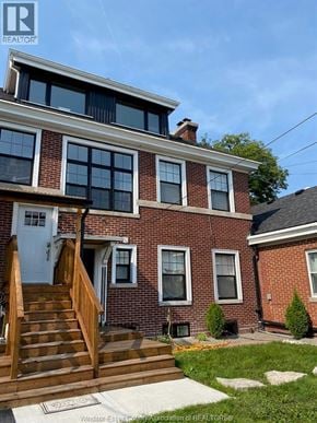 Windsor apartment for rent - A brick house with a blue door and a wooden staircase leading to it.