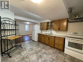 Barrie (Northwest) apartment for rent - A kitchen with a white stove top oven and wooden cabinets.