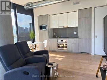 Toronto (Moss Park) condo for rent - A modern living room with a grey sofa and a wooden floor.