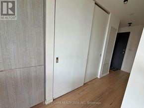 Toronto (Moss Park) condo for rent - A room with a wooden floor and white walls, with a door on the right.