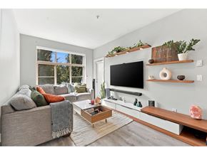 Surrey apartment for rent - A living room with a grey couch, a coffee table, and a flat screen TV mounted on the wall.