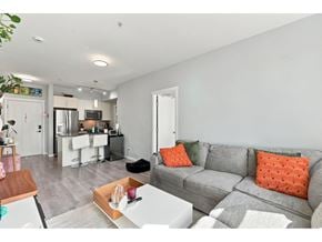 Surrey apartment for rent - A grey couch with orange pillows sits in a living room.