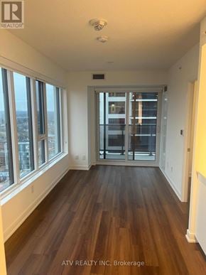 Toronto (Islington-City Centre West) condo for rent - A spacious room with wooden floors and large windows overlooking a cityscape.