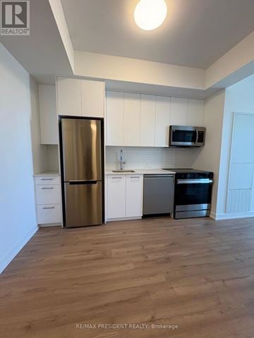 Kitchener condo for rent - A kitchen with white cabinets and a wooden floor.