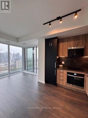 Toronto (Kensington-Chinatown) condo for rent - A modern kitchen with wooden cabinets and a black refrigerator.