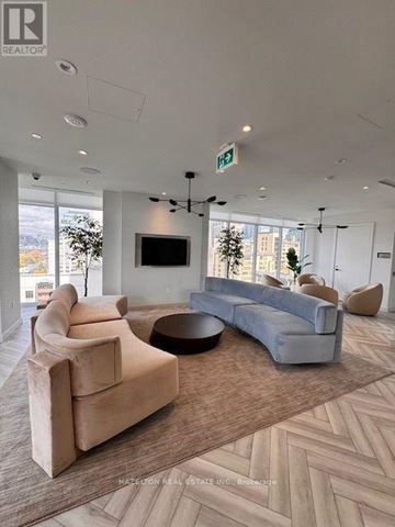 Toronto (Kensington-Chinatown) condo for rent - A living room with a grey sofa and a brown armchair.