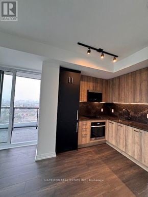 Toronto (Kensington-Chinatown) condo for rent - A modern kitchen with wooden cabinets and a black door.