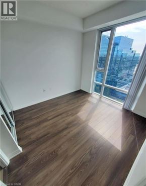 Toronto condo for rent - A room with wooden flooring and a large window overlooking a cityscape.