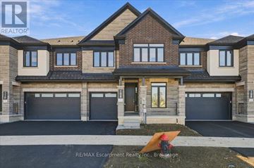 Hamilton (Waterdown) townhouse for rent - A large, modern house with a brick facade and multiple garage doors.