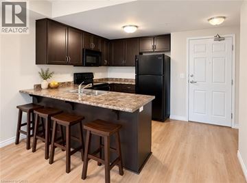Guelph condo for rent - A kitchen with a black refrigerator and brown bar stools.