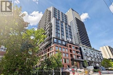 Toronto (Mount Pleasant West) condo for rent - A modern multi-story building with a glass facade is surrounded by other buildings and trees.