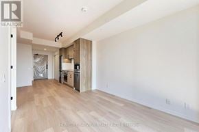 Toronto (Mount Pleasant West) condo for rent - A room with wooden flooring and white walls, with a kitchen area visible in the background.