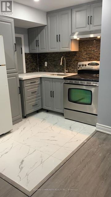 Oshawa (Windfields) apartment for rent - A kitchen with a white refrigerator, grey cabinets and a black stove top oven.