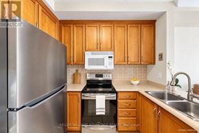 Bradford West Gwillimbury (Bradford) condo for rent - A kitchen with wooden cabinets and a stainless steel refrigerator.