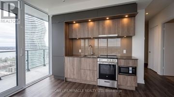 Mississauga (City Centre) condo for rent - A modern kitchen with wooden cabinets and stainless steel appliances.