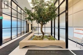 Oakville (Jm Joshua Meadows) condo for rent - A tree in a planter sits in the middle of a hallway.