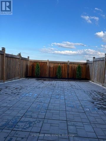 Hamilton (Stoney Creek Mountain) townhouse for rent - A backyard with a wooden fence and a tiled patio.