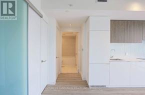 Toronto (Mount Pleasant West) condo for rent - A hallway with a door on the left and a kitchen area on the right.