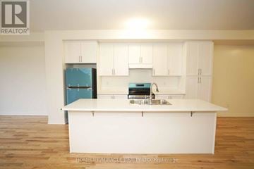 Clarington (Bowmanville) townhouse for rent - A kitchen with white cabinets and a blue fridge.