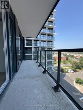 Toronto (York University Heights) condo for rent - A balcony with a glass railing and a view of a parking lot and buildings.