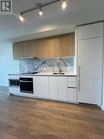 Toronto (York University Heights) condo for rent - A kitchen with white cabinets and a marble backsplash.