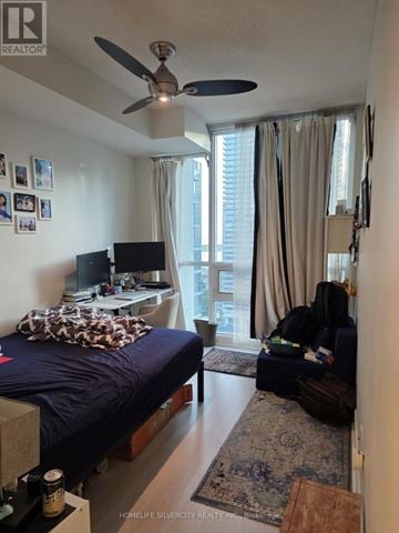 Toronto (Waterfront Communities) condo for rent - A bedroom with a bed, a fan, a couch, and a television.