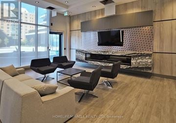 Mississauga (Hurontario) condo for rent - A living room with a large couch, a chair, and a television mounted on the wall.