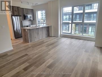 Mississauga (Hurontario) condo for rent - A spacious living room with wooden flooring and a kitchen area with a refrigerator and microwave.