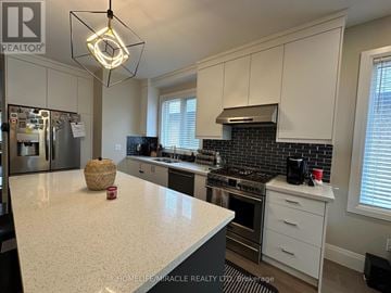 Hamilton (Eleanor) apartment for rent - A kitchen with white cabinets and a black and white checkered backsplash.