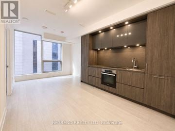 Toronto (Waterfront Communities) condo for rent - A modern kitchen with wooden cabinets and a stainless steel oven.