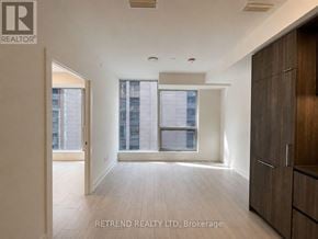 Toronto (Waterfront Communities) condo for rent - A spacious room with wooden flooring and a large window with a view of a cityscape.