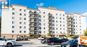 Waterloo multi-family for rent - A white and beige apartment building with cars parked in front.