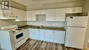 Kitchener multi-family for rent - A kitchen with white appliances and cabinets.