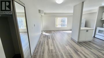 Waterloo multi-family for rent - A spacious room with wooden flooring and a kitchen area with white cabinets.