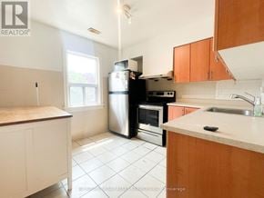 Toronto (Trinity-Bellwoods) apartment for rent - A kitchen with white tiles and wooden cabinets.