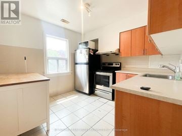 Toronto (Trinity-Bellwoods) apartment for rent - A kitchen with white tiles and wooden cabinets.