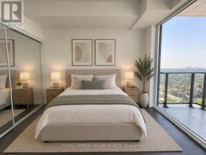 Toronto (Humber Heights) condo for rent - A bedroom with a large bed, two nightstands, and a view of the city.