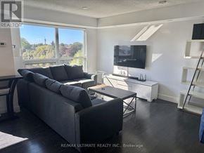 Toronto (Bathurst Manor) condo for rent - A living room with a grey couch and a television.