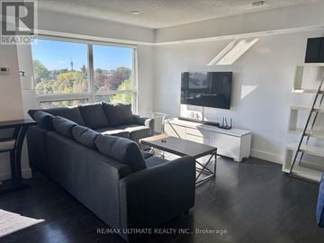 Toronto (Bathurst Manor) condo for rent - A living room with a grey couch and a television.