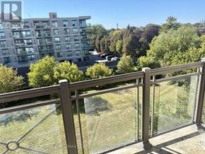 Toronto (Bathurst Manor) condo for rent - A balcony with a glass railing overlooks a grassy area and a building.