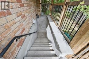 Kitchener apartment for rent - A staircase with a metal railing and a brick wall on one side.