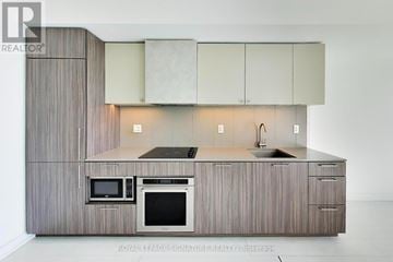 Toronto (Niagara) condo for rent - A modern kitchen with a microwave and oven built into the cabinetry.