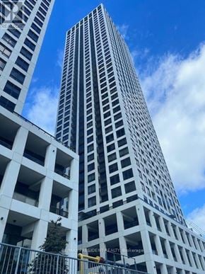 Mississauga (Fairview) condo for rent - A tall white building with balconies is seen against a blue sky.