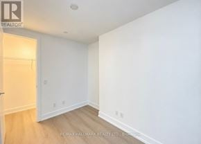 Toronto (Bay Street Corridor) condo for rent - A white room with a wooden floor and a door on the left.