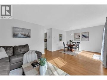 North Vancouver townhouse for rent - A living room with a grey couch and a coffee table with a vase of flowers on it.