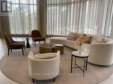 Toronto (Bayview Village) condo for rent - A living room with a white couch, a brown chair, and a small table with a vase of flowers on it.