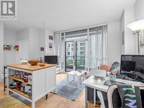 Toronto (Niagara) condo for rent - A well-lit, modern apartment with a kitchenette, a desk, and a view of the city.