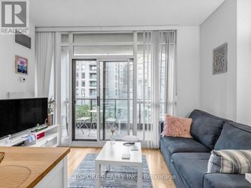 Toronto (Niagara) condo for rent - A living room with a grey couch and a flat screen TV.